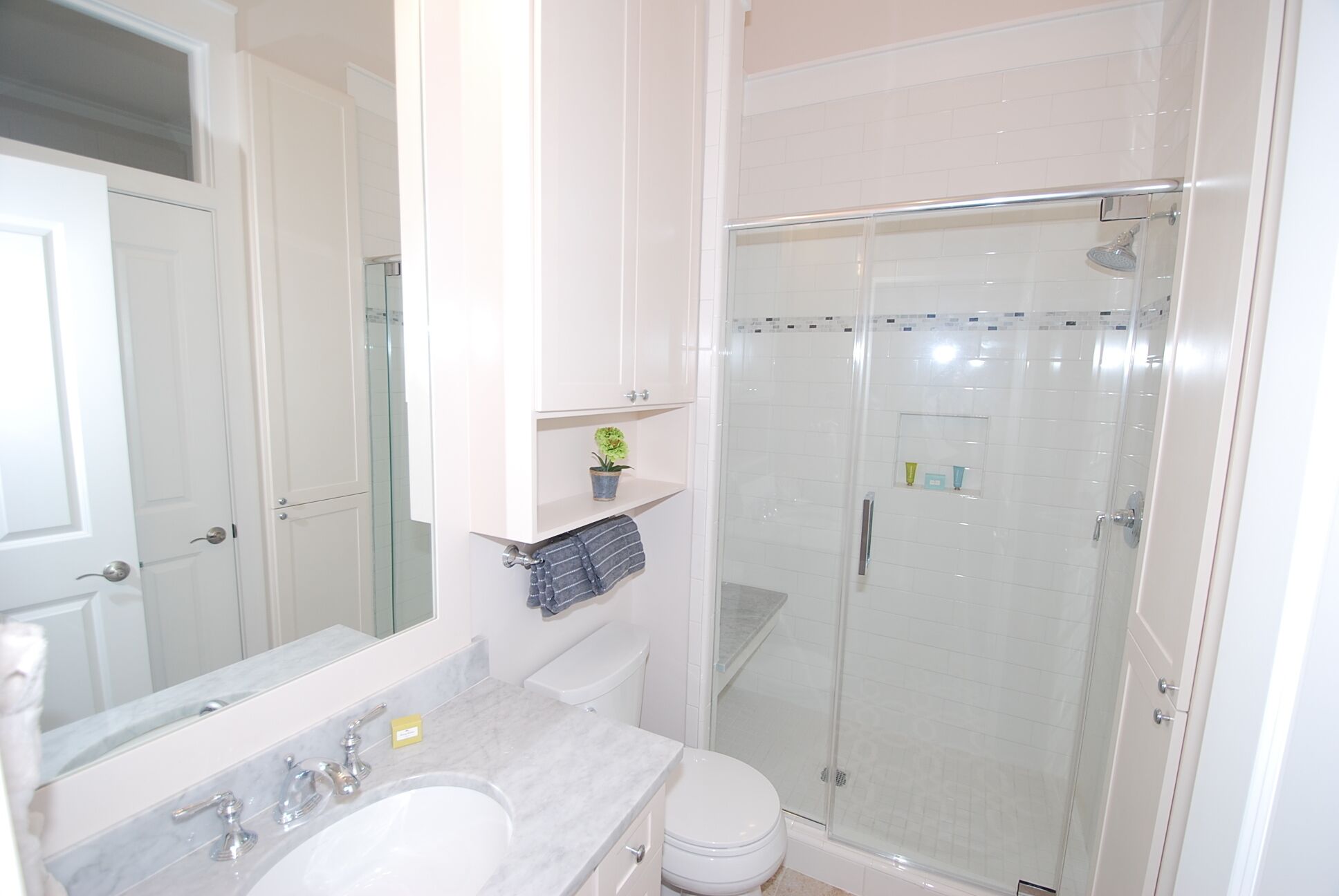 A bathroom with a glass-enclosed shower, a white sink, and a mirror above the sink.