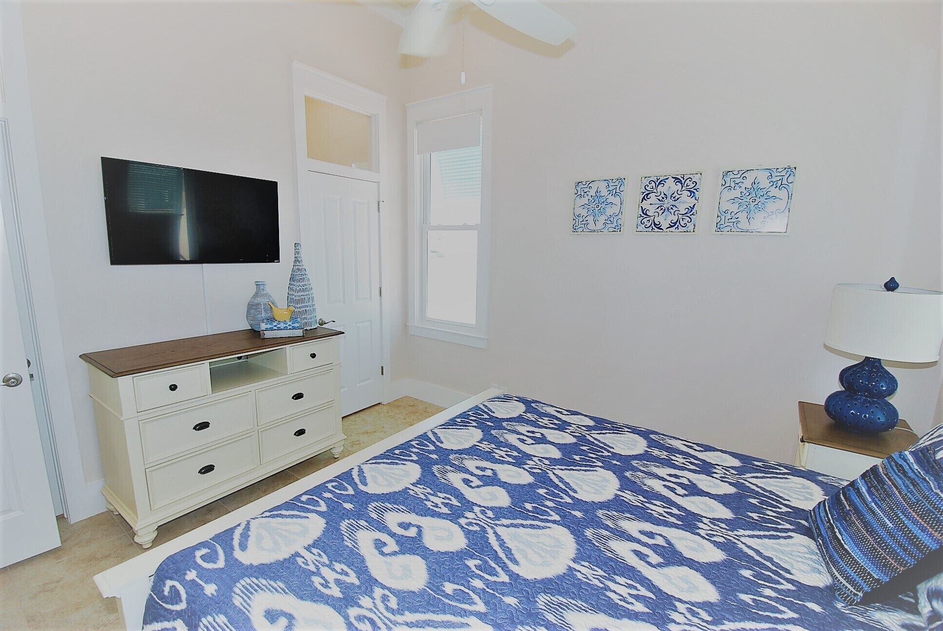 A bedroom with a bed, dresser, TV, and decorative items.
