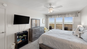 Quarto com cama, televisão, cômoda e ventilador de teto.