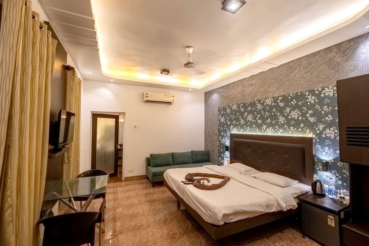 A hotel room with a bed, a sofa, a desk, and a TV.