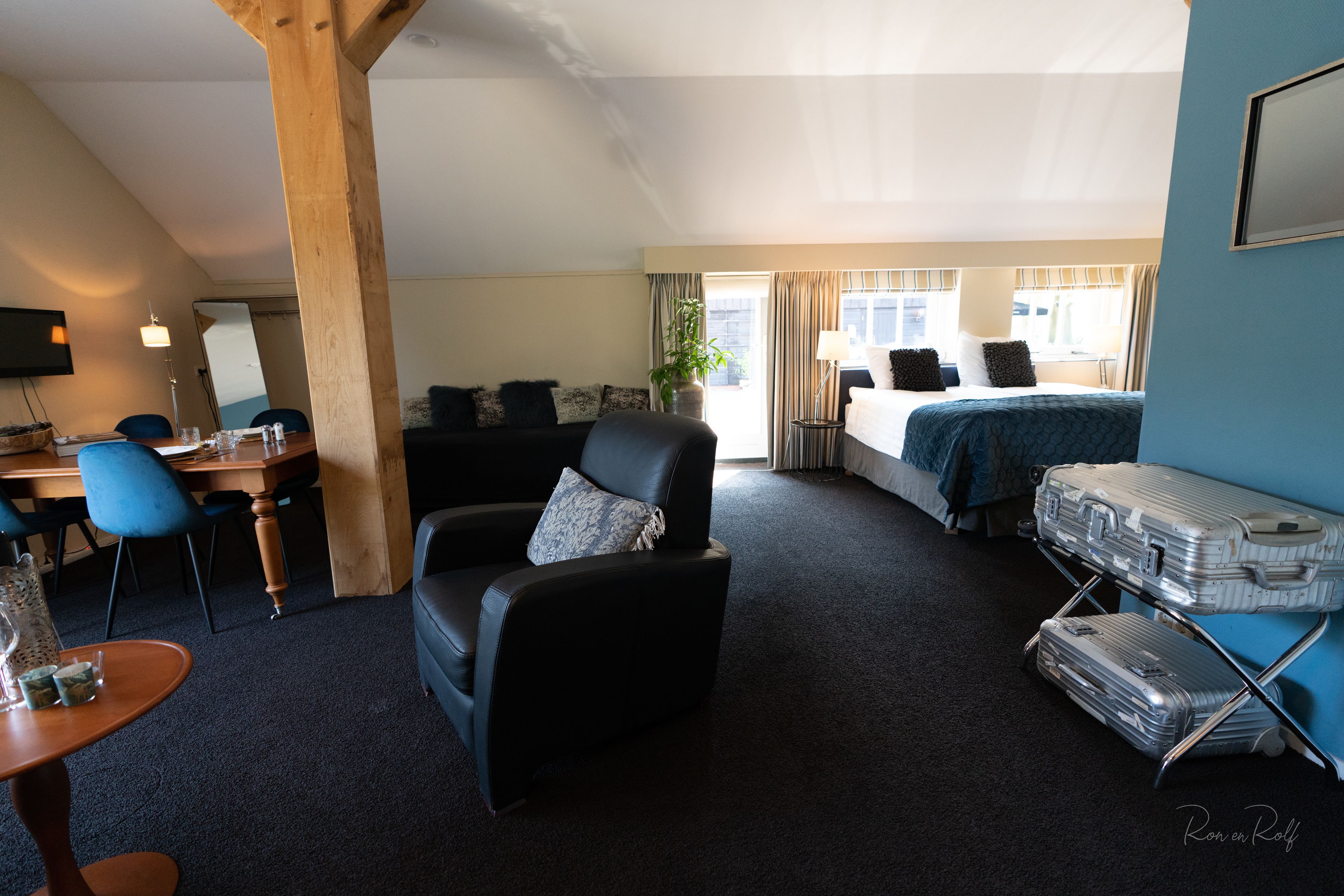 A hotel room with a bed, a desk with a chair, a sofa, and a luggage rack.