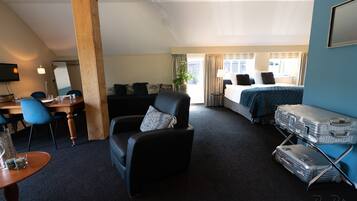 A hotel room with a bed, a desk with a chair, a sofa, and a luggage rack.