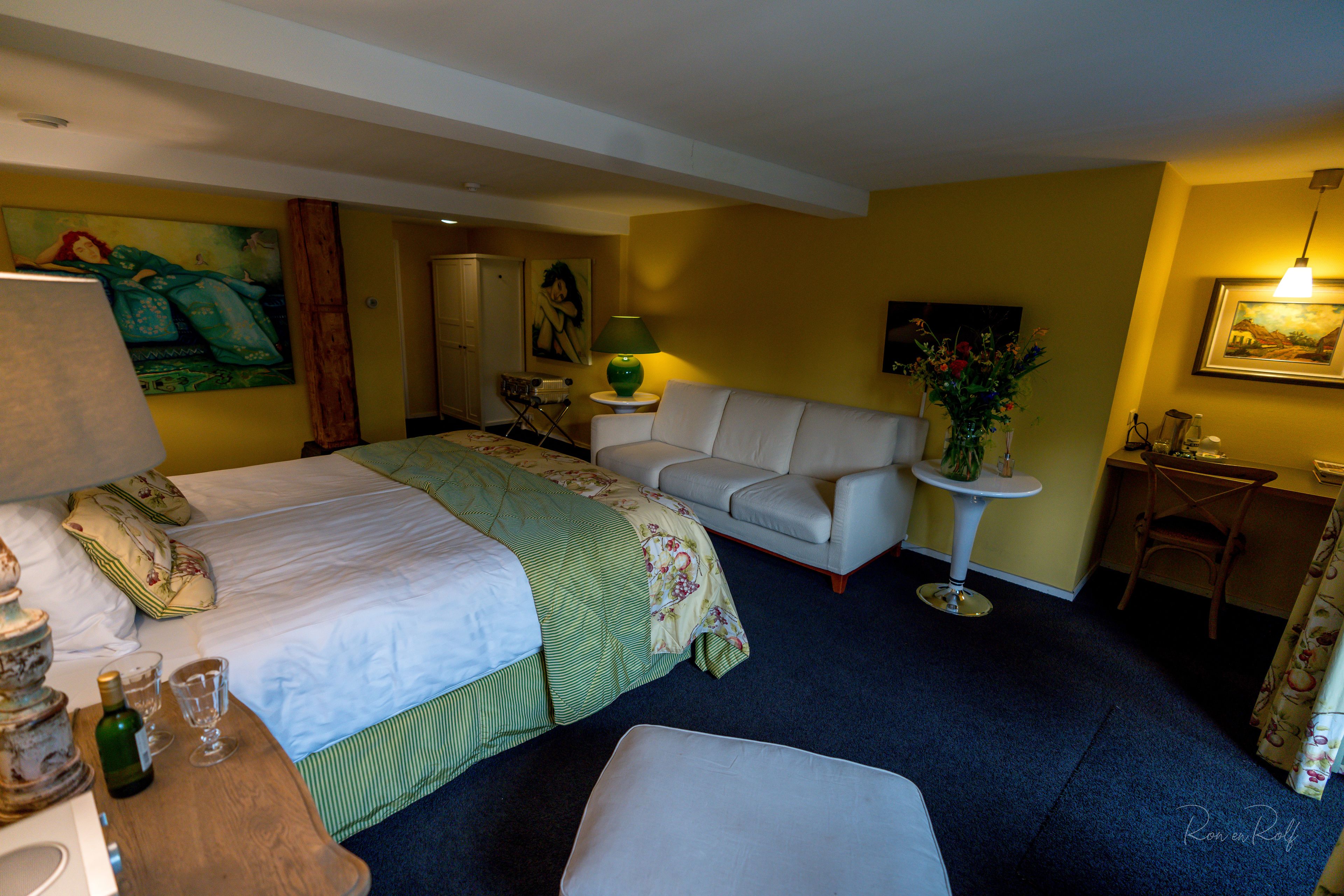 Une chambre d’hôtel comprenant un lit, un canapé, une petite table avec une lampe, une chaise et un bureau.