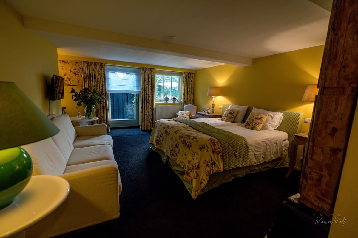 Une chambre d’hôtel avec un lit, un canapé, une table et une lampe.
