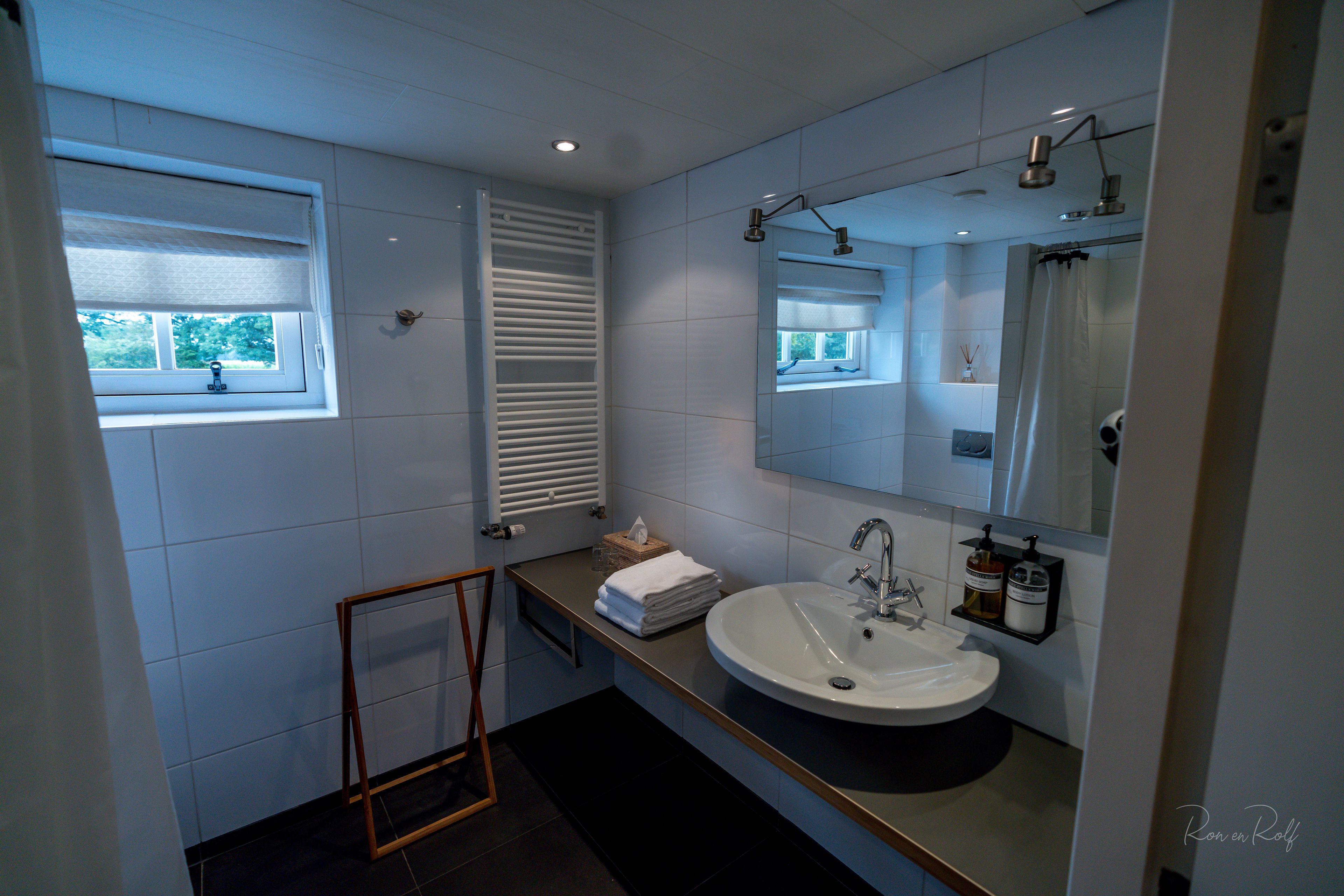A modern bathroom with a large sink, mirror, and window.