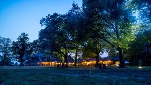 Een ruime woning met meerdere kamers, omgeven door bomen en gazon.