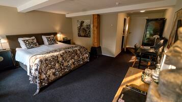 A hotel room with a large bed, a desk with a computer, and a painting on the wall.