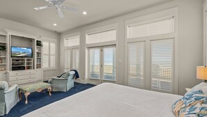 A bedroom with a large bed, a desk, a chair, a TV, and a balcony. - Paradise Found - Private Beachfront House 3 Bedroom Home by RedAwning (South Padre Island)