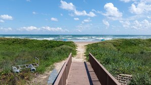 Une promenade en bois qui mène à une plage offrant une vue sur l’océan.