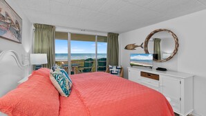 Une chambre avec un grand lit, une télévision, une commode et une vue sur l’océan.