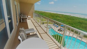 A balcony with a view of the beach, a pool, and outdoor seating. - Edgewater Unit #303 2 Bedroom Apts by RedAwning (South Padre Island)