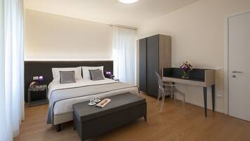 A modern hotel room with a large bed, a desk, and a bench.