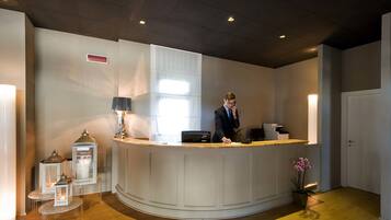 Een receptie met een gebogen balie, een receptioniste, een bureau met een computer en decoratieve lantaarns.