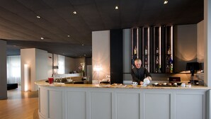 A modern bar area with a counter, bar stools, and a variety of bottles on shelves. - Hotel La Corte (Cascia)