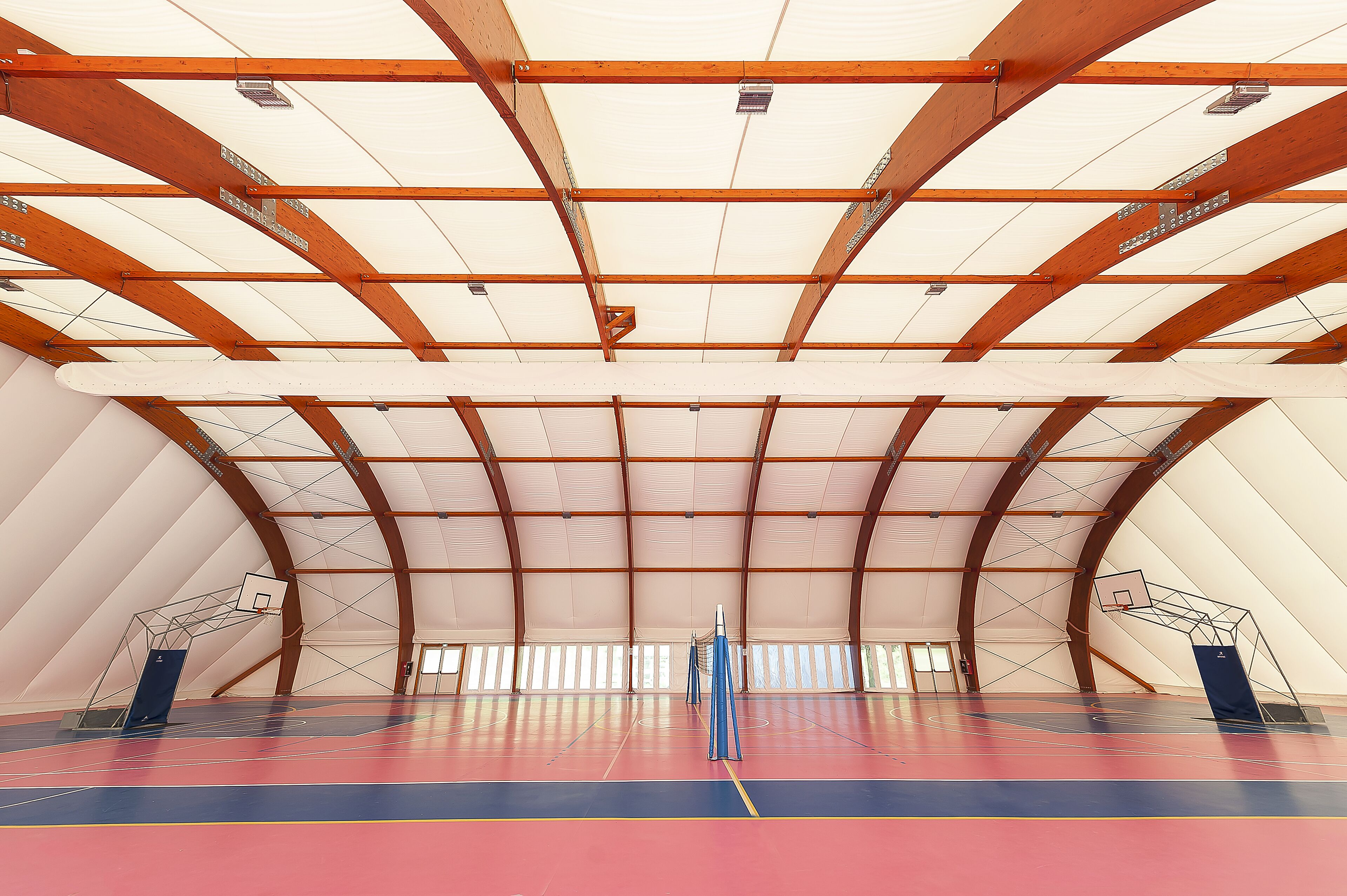 An indoor basketball court with a high ceiling and wooden beams.