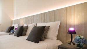 A hotel room with a wooden headboard, a bed with white bedding and multiple pillows, a nightstand with a lamp and a vase of flowers. - Hotel La Corte (Cascia)