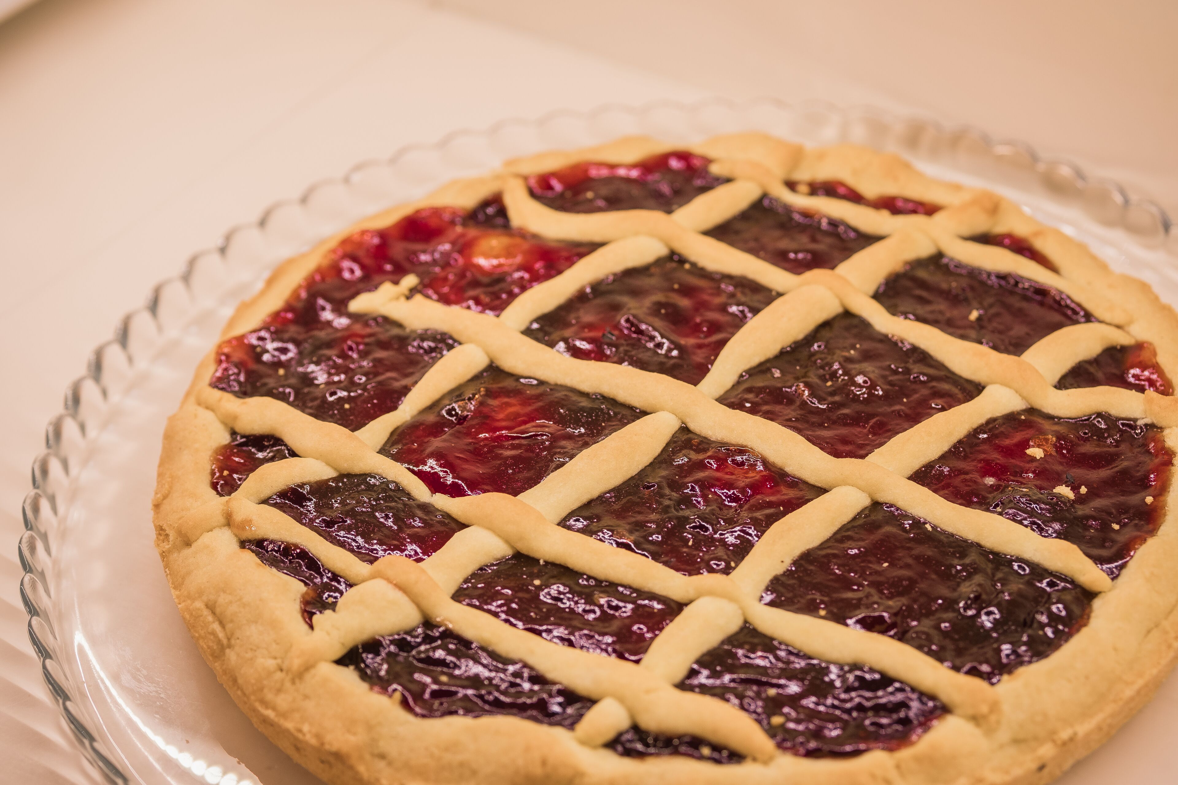 A pie with lattice crust on a clear glass plate.