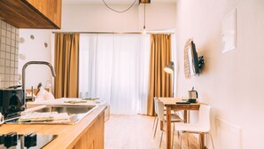 Una cocina moderna con encimera de madera, horno empotrado y un lavamanos. Hay un comedor con una mesa y sillas de madera.