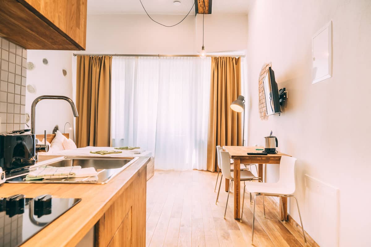 A modern kitchen with a wooden countertop, a built-in oven, and a sink. There is a dining area with a wooden table and chairs.