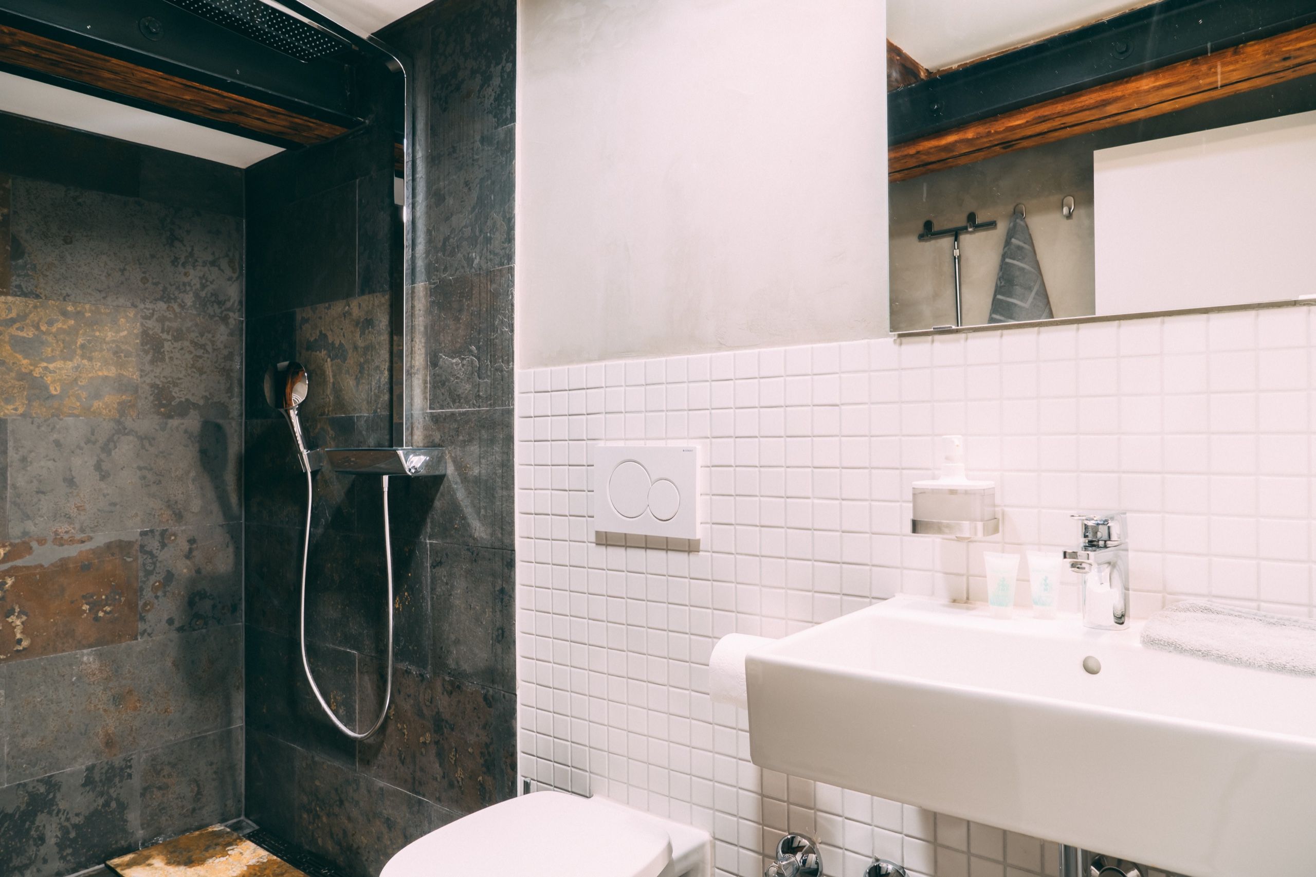 A bathroom with a shower, toilet, sink, and a towel rack.