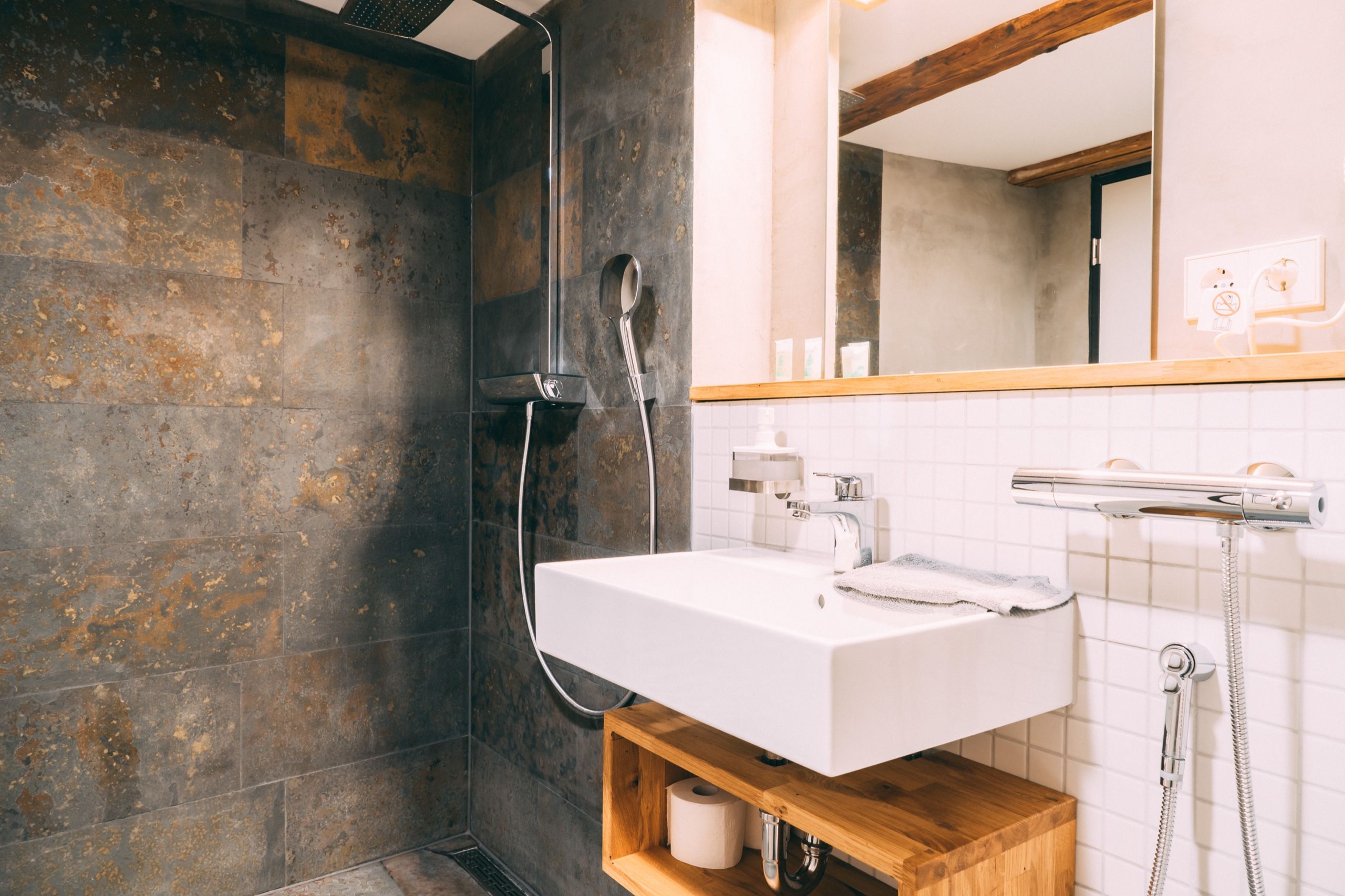 Un baño moderno con ducha, lavamanos y espejo.