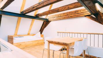 A small, cozy attic bedroom with a wooden bed, a small table, and two white chairs.
