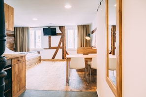 Un interior moderno con una mesa de comedor de madera, sillas, un televisor montado en la pared y una escalera que sube a un nivel superior.