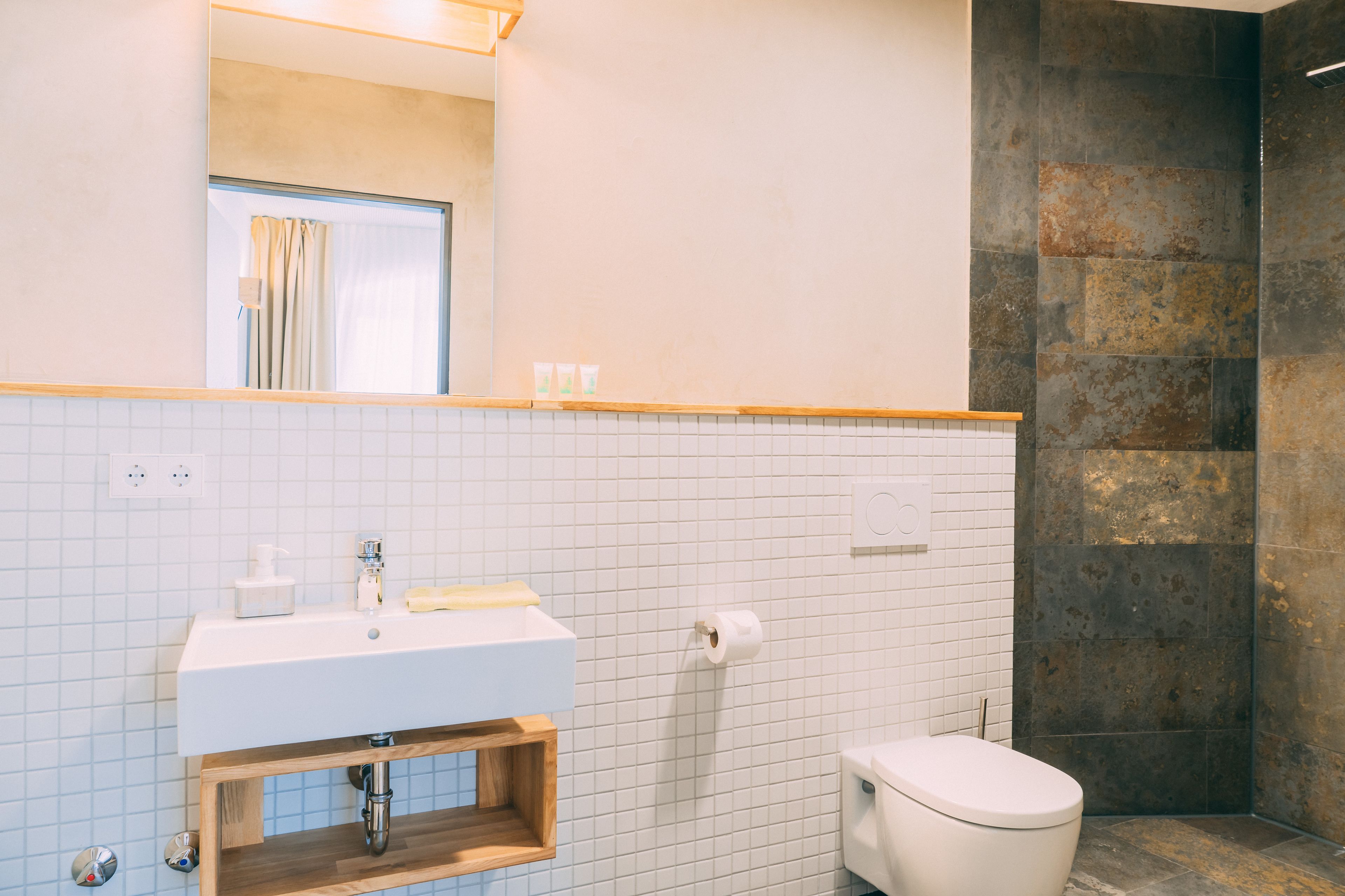 A bathroom with a white sink, mirror, and toilet.