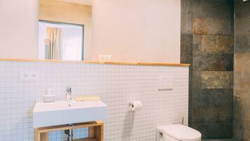 A bathroom with a white sink, mirror, and toilet.