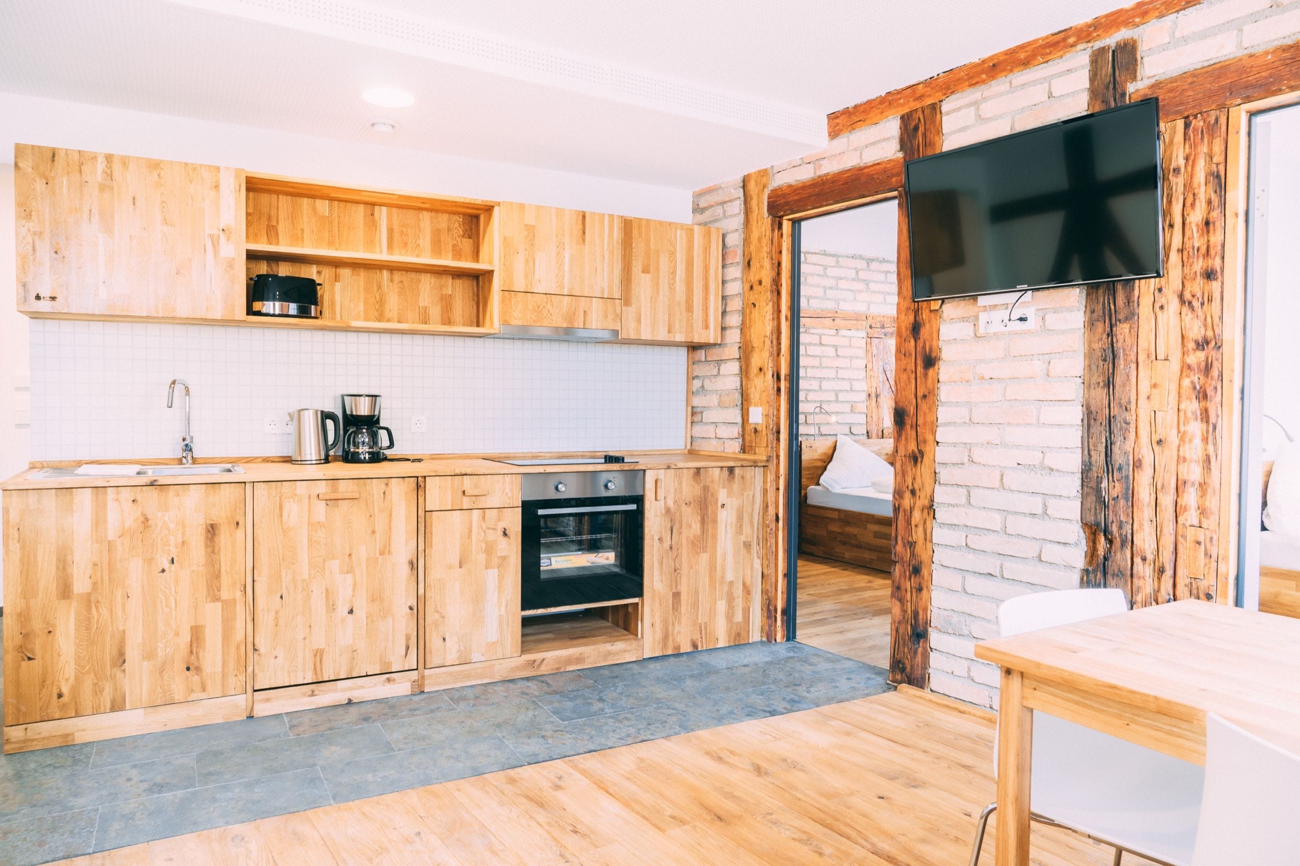 Een moderne keuken met houten kastjes, een inbouwoven en een groot raam.