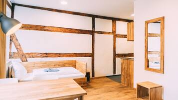 Une pièce avec un plafond en bois, un lit avec une literie blanche, une table en bois et une petite armoire en bois.