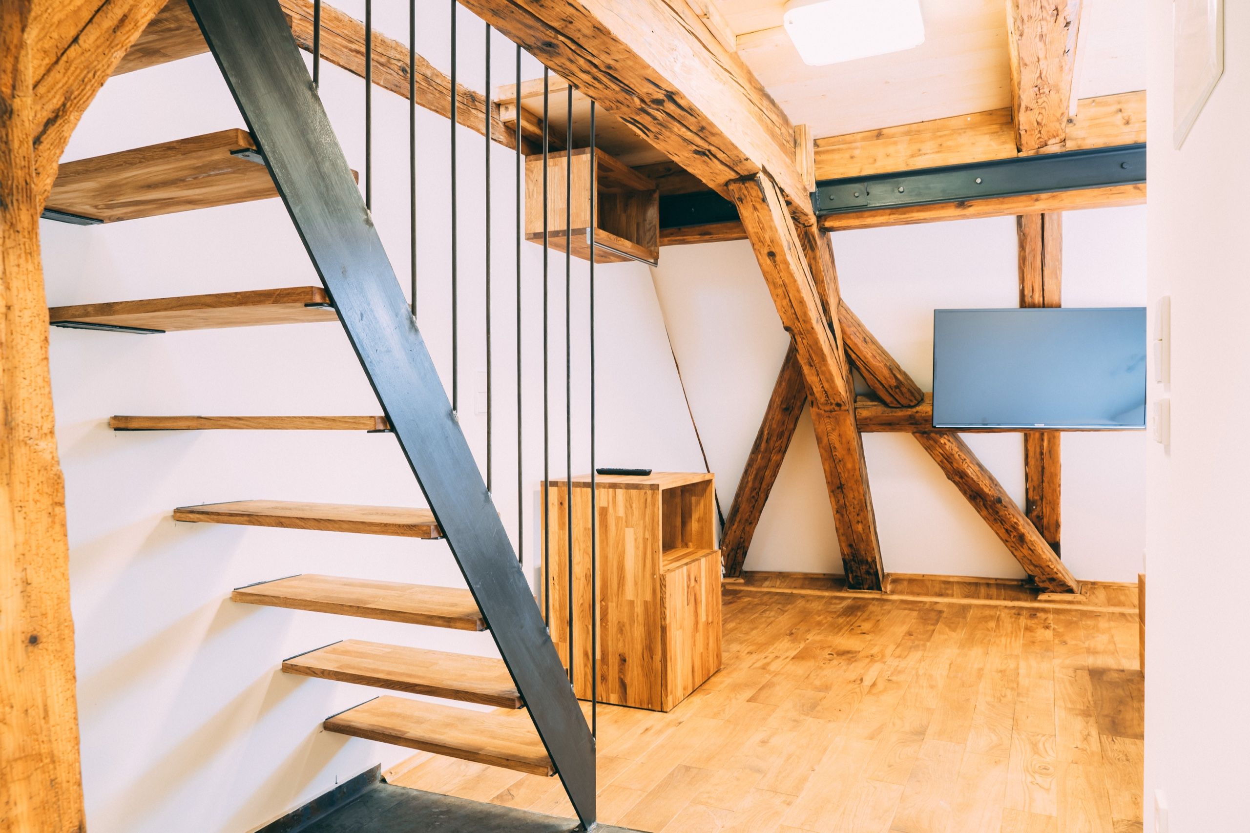 A wooden staircase with metal railings, a small wooden box, and a blue panel on the wall.