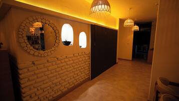 A hallway with a brick wall, a circular mirror, and two pendant lights.
