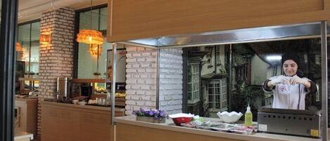A modern kitchen with a brick wall, wooden counter, and hanging pendant light.