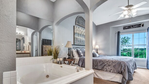 Ein modernes Badezimmer mit einer großen Badewanne, einem Spiegel und einem Deckenventilator.