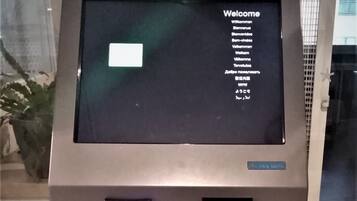 A self-service kiosk with a digital display, a card reader, and a cash slot.