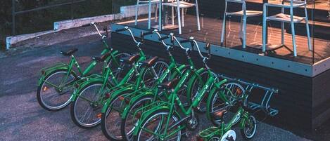 A row of green bicycles parked outside a building with outdoor seating.