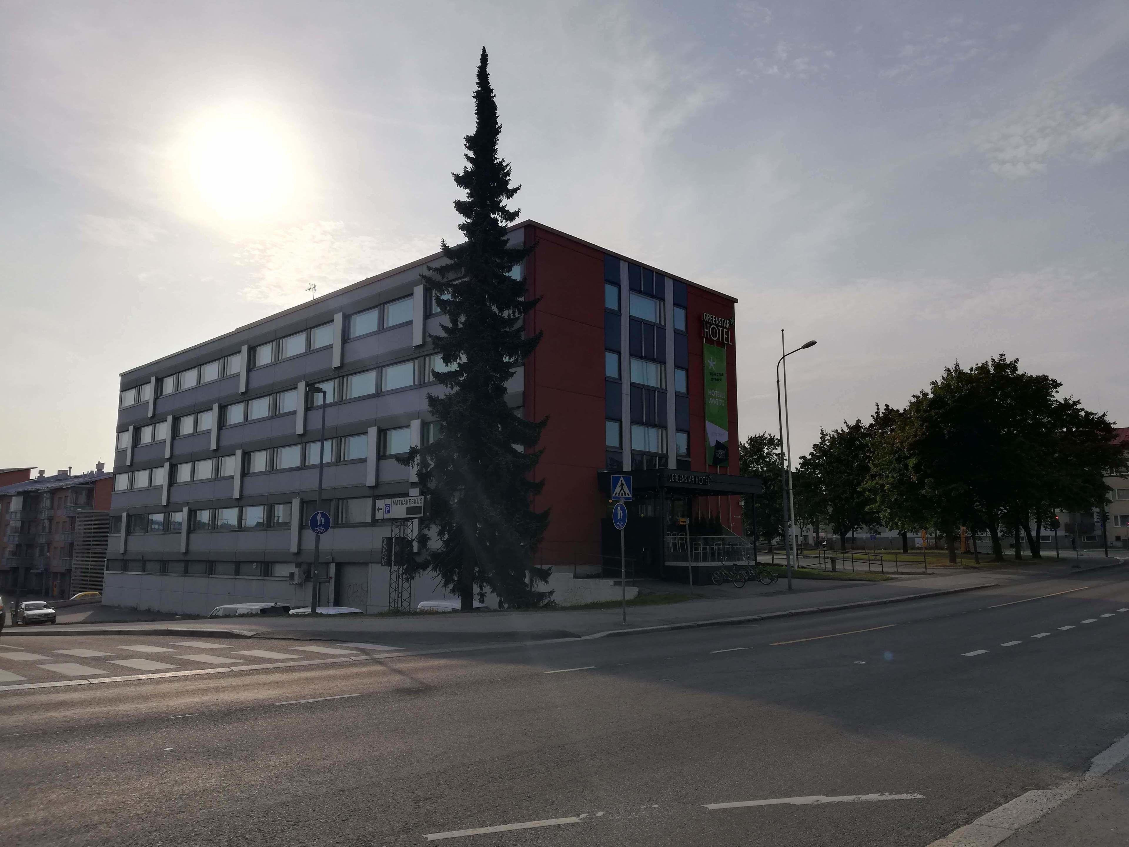 Un hotel de varios pisos con fachada roja y gris, situado en una esquina.