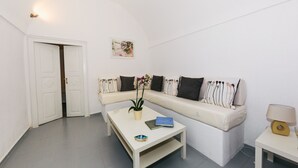 Una sala de estar minimalista con un sofá blanco, una mesa de centro y una pequeña mesita auxiliar.
