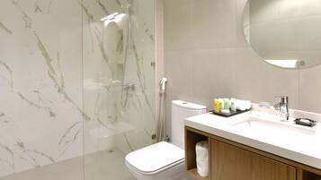 A modern bathroom with a glass-enclosed shower, a white toilet, a wooden vanity with a mirror, and a white sink.