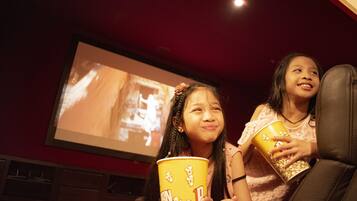 Two people seated in a theater with a large screen in the background.