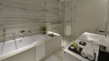 A modern bathroom with a glass-enclosed shower, a bathtub, and a vanity with toiletries.