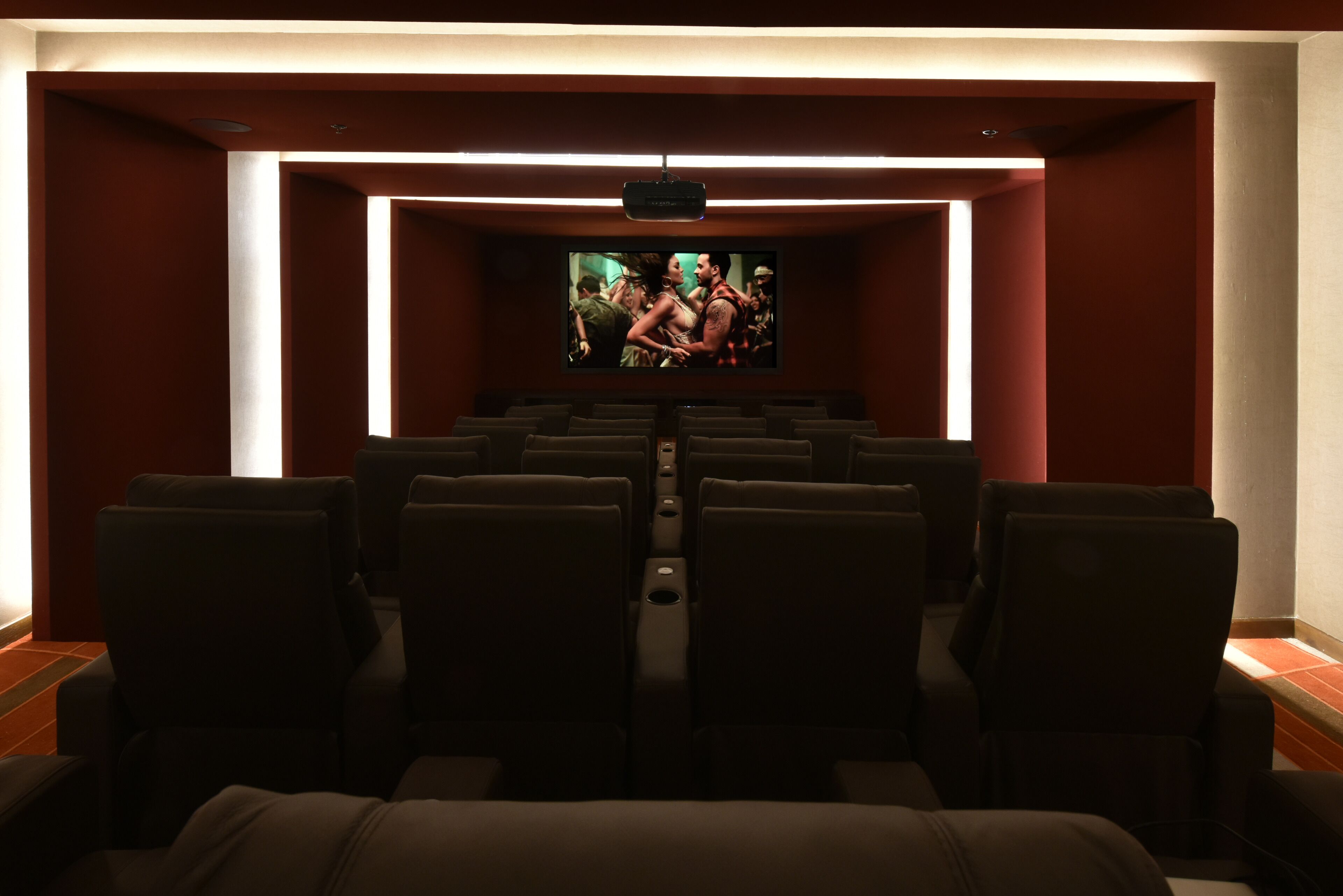 A cinema with rows of black seats and a large screen at the front.
