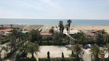 Blick auf die Küste mit Strand, Palmen und einem Parkplatz.