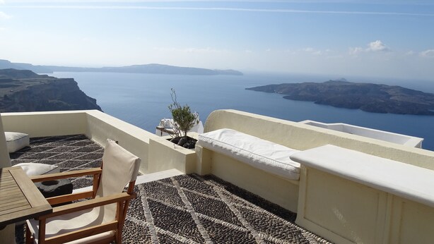 A terrace with a view of the sea and islands, a table, chairs, and a small plant. - 360 Blue (Santorini)