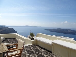Eine Terrasse mit Blick auf das Meer und Inseln, inklusive Tisch, Stühlen und einer kleinen Pflanze.