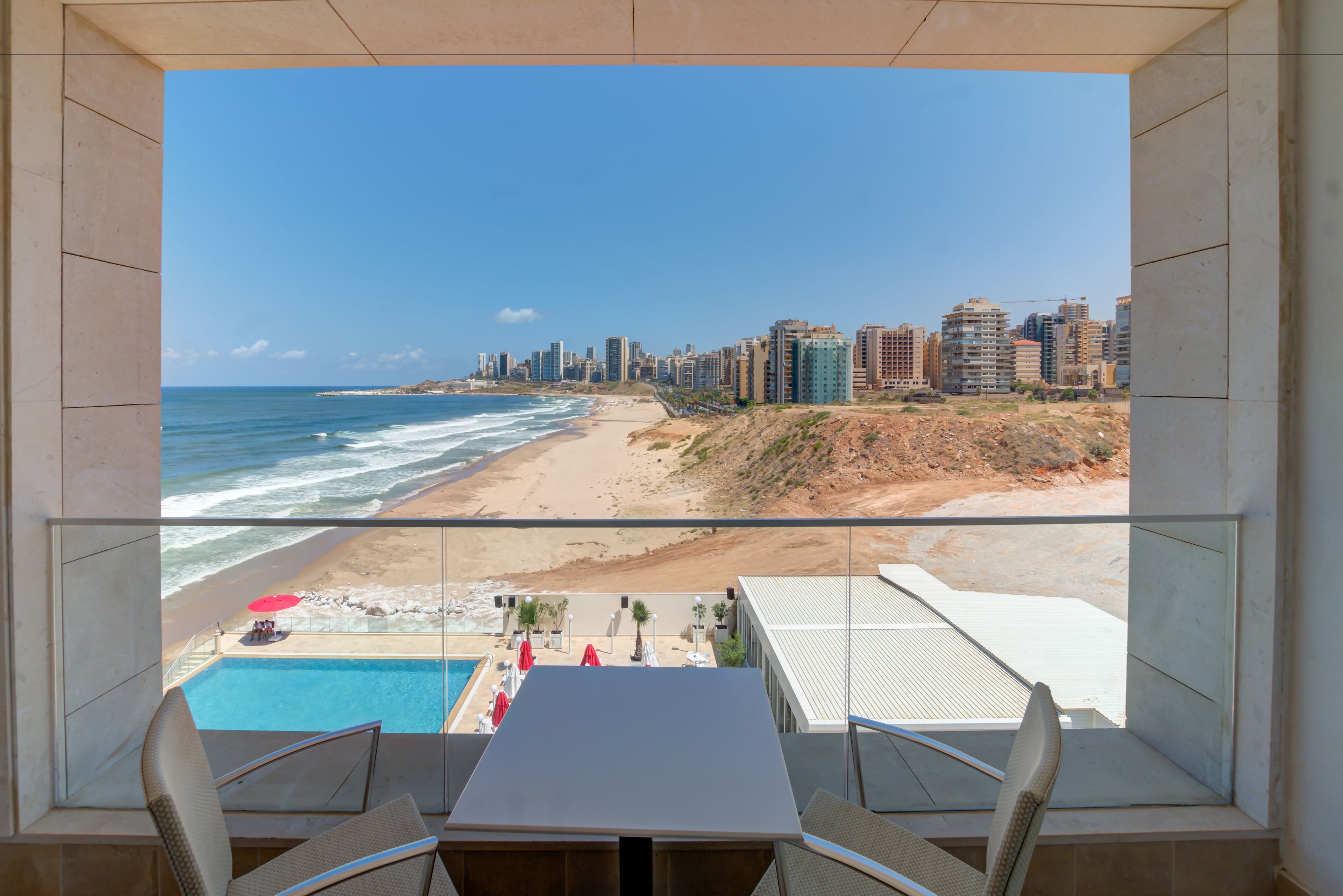 A balcony with a view of a beach and a cityscape.