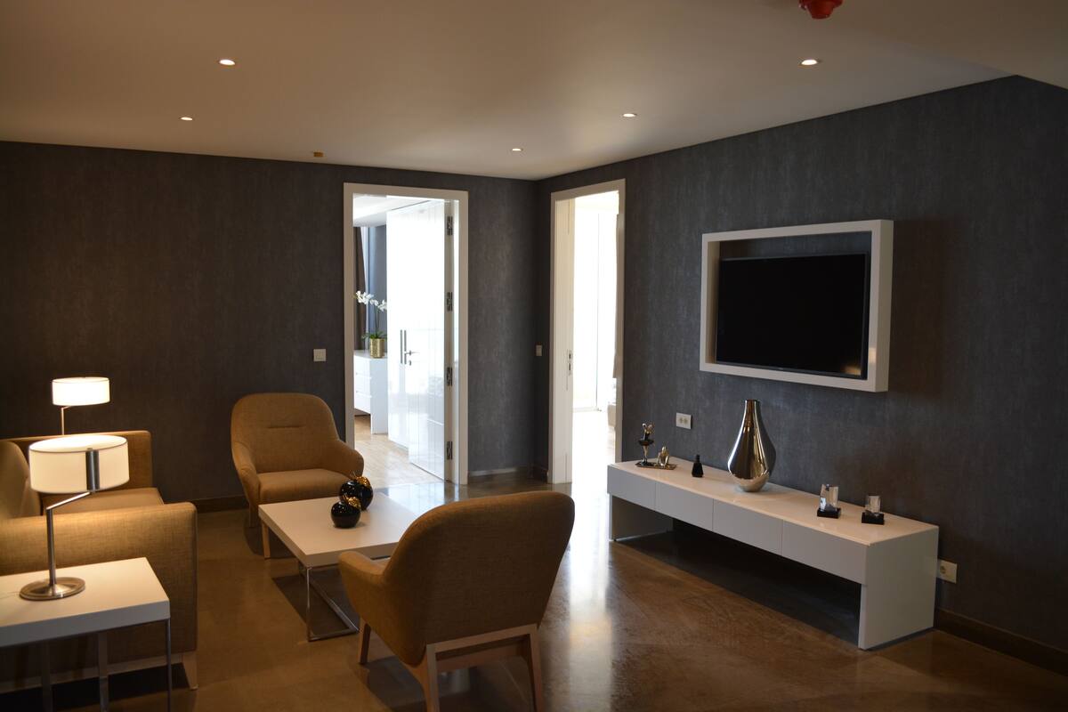A modern living room with a flat-screen TV, a sofa, a coffee table, and a lamp.