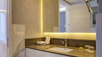 Un baño moderno con lavabo de mármol, un espejo grande y un perchero para toallas.