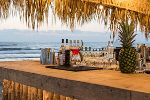 Un bar con mostrador de madera, botellas, vasos y una piña.